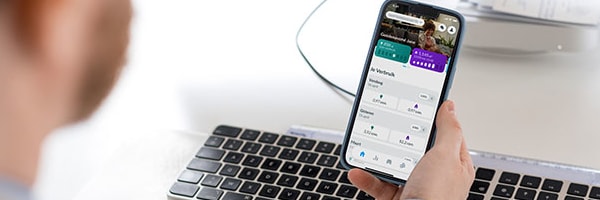 Een man op zijn bureau die een telefoon vasthoudt en bezig is met zijn Smart App