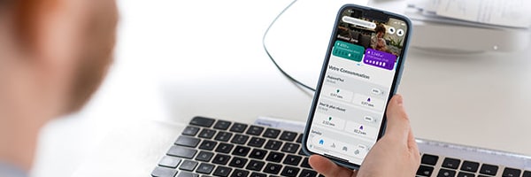 Un homme sur son bureau tient un téléphone et est sur son Smart App