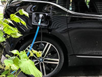 Een zwarte auto met blauwe oplaadslang