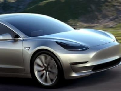 Een zilveren Tesla die over een weg rijdt