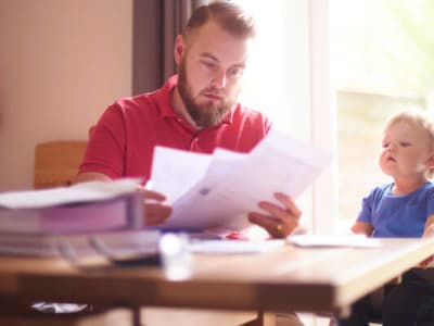 Un homme et un enfant assis à une table, examinant des documents ensemble.