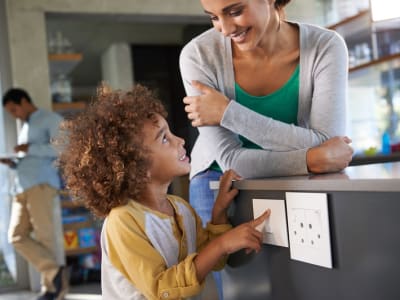 Une femme et un enfant se tiennent devant une prise électrique murale