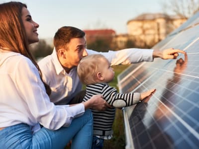 Een man en een vrouw met een baby tonen zonnepanelen