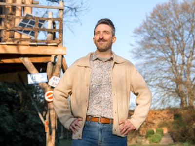 Een man staat voor een boomhut