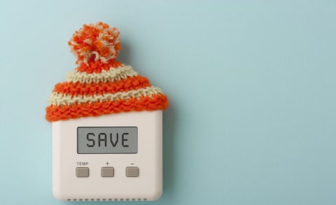 Un bonnet tricoté sur un thermostat indiquant &quot;save&quot;