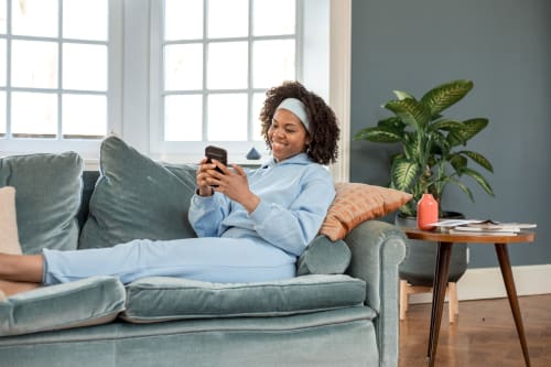 een dame in een bank die naar haar telefoon kijkt