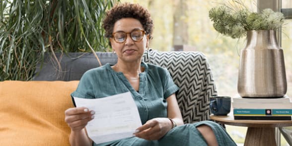 Vrouw met bril leest geconcentreerd en geïnteresseerd een brief