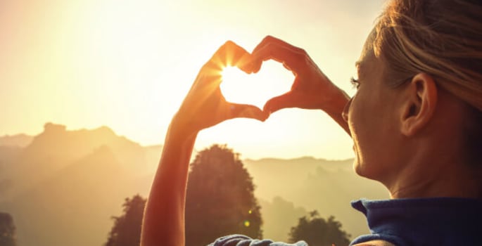 Vrouw zonsondergang hart met de vingers