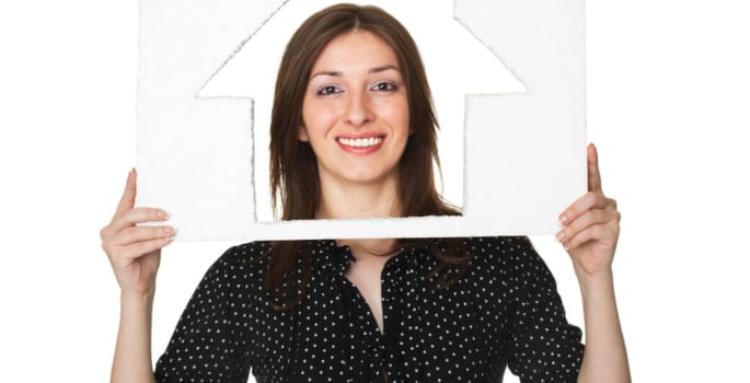 Une femme tenant une maison en papier découpée