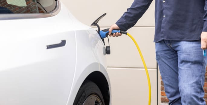 Un homme qui recharge sa voiture électrique