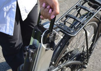 Vrouw die de batterij uit haar elektrische fiets haalt