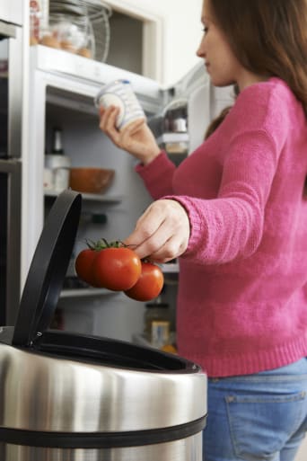 Femme jetant des aliments du frigo à la poubelle