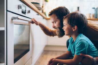 Vader en zoon die een bereiding in de oven in de gaten houden