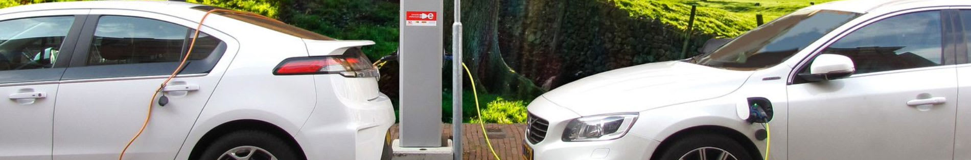 Deux voitures blanches se chargent à une borne de recharge : l'une derrière l'autre.