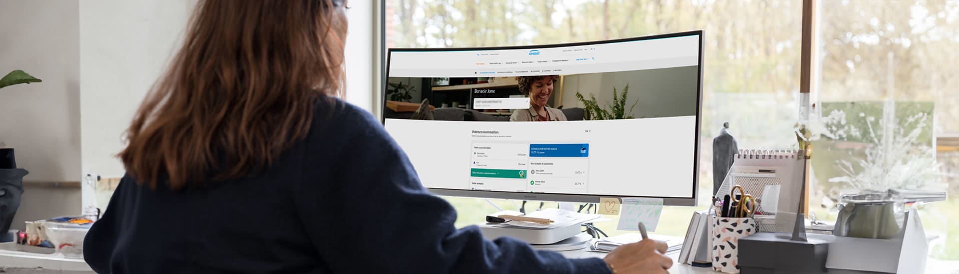 Une femme assise à son bureau regarde l'écran de son ordinateur et se trouve dans sa zone de clientèle d'ENGIE.