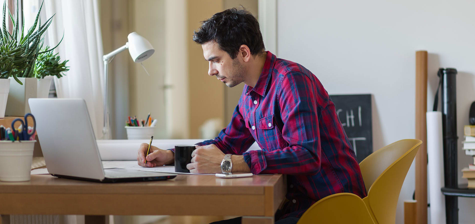 Un homme est assis à un bureau et écrit sur une feuille de papier.