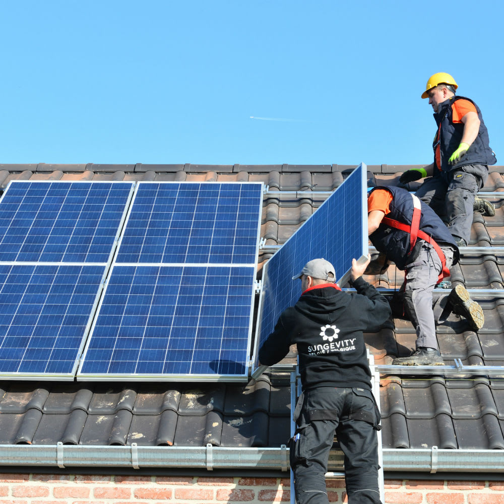 Trois hommes installent des panneaux solaires sur un toit, travaillant ensemble pour une énergie durable.