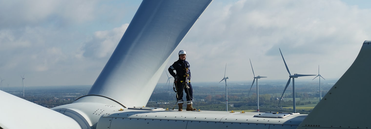 Un homme se tenant au sommet d&#039;une éolienne, contemplant le paysage environnant avec une vue panoramique.