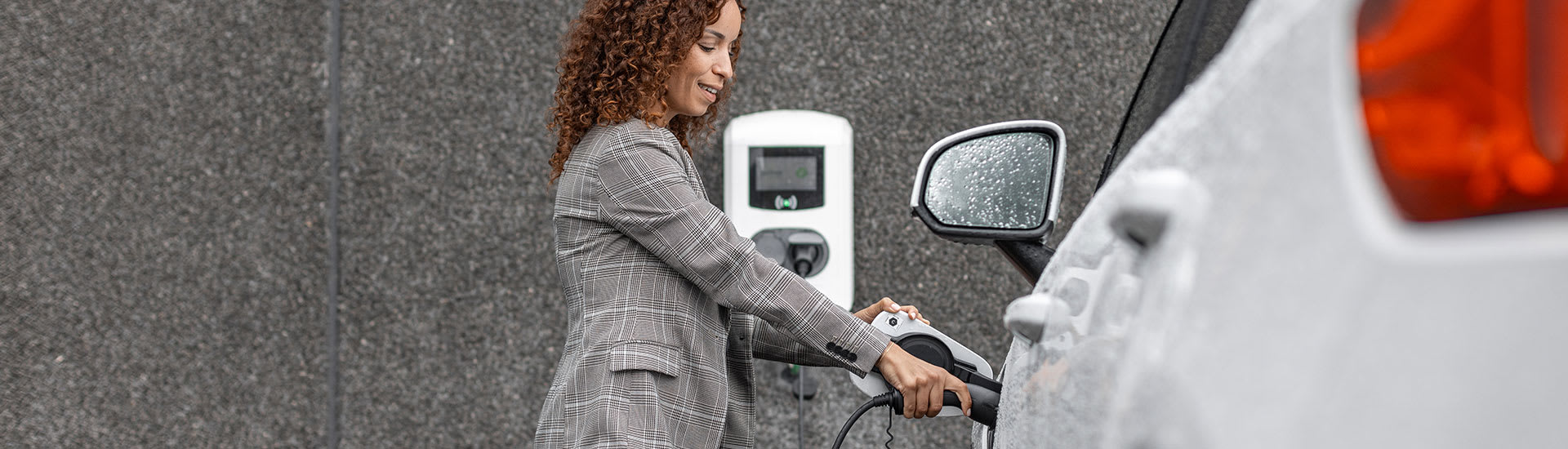 Een vrouw laadt haar witte auto op aan een wit oplaadpunt