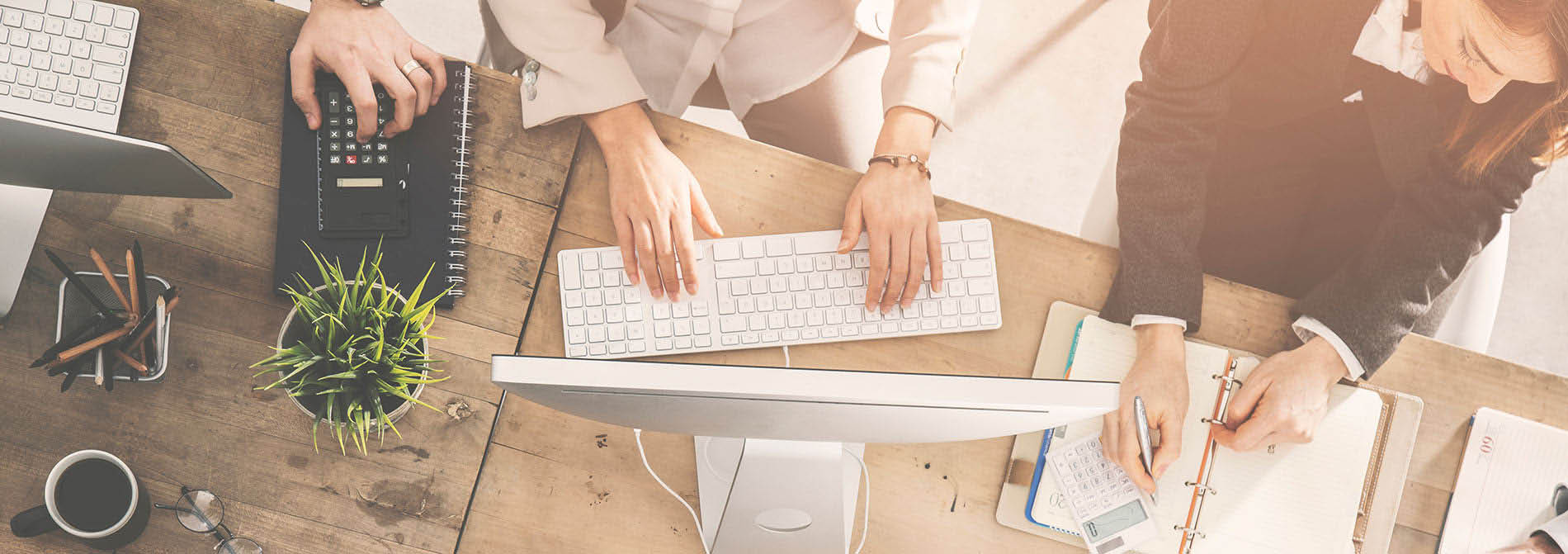 Werknemers werken samen aan een bureau, gebruiken computers en bestuderen papieren.