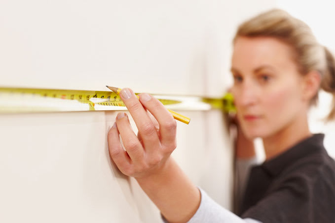 Vrouw meet de oppervlakte van haar huis