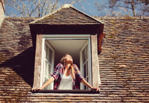 Vrouw_raam_zon_verwarming_natuurlijke verwarming_warmte