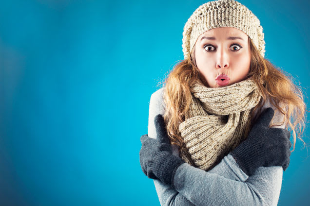 Jonge vrouw met muts en sjaal die het koud heeft