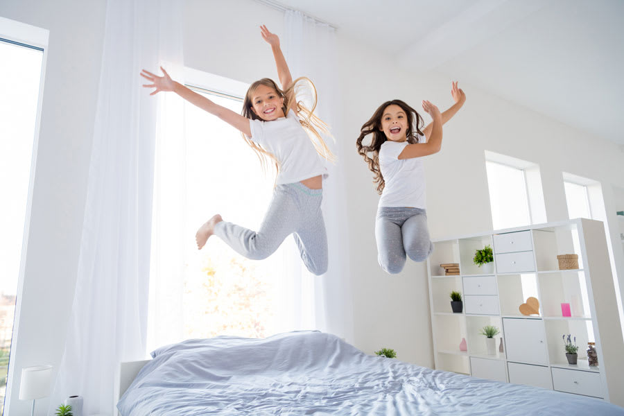 energieke meisjes springen op het bed in hun slaapkamer